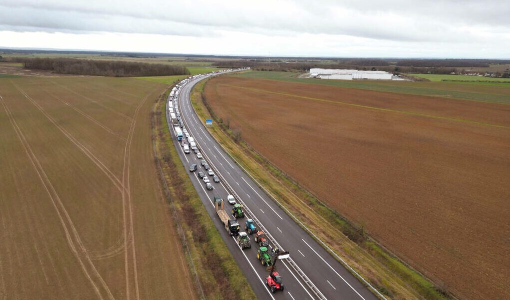An aerial picture shows farmers driving their tractors to disturb traffic on the A71 highway to protest over taxation and declining income, in Levet near Bourges, on January 24, 2024. Europe's farmers are in revolt. The fury has led to road blockages and tractor parades in the past few weeks, with farmers taking their protests to the street in France, Germany, Poland and Romania, after the Netherlands earlier. From rising fuel costs to anger over green regulations to what farmers' say is unfair competition from Ukrainian imports, the list of grievances is long. (Photo by GUILLAUME SOUVANT / AFP)